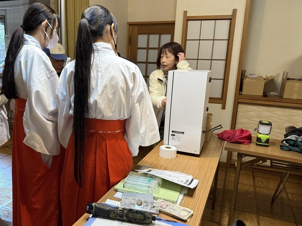 上野東照宮の敷地内で券売機の操作方法について講習会を開くアトラスの中森さん