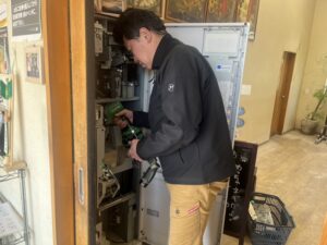 茨城県つくば市「らーめん逆流」様の店内で券売機VT-B20の修理を行うアトラスのスタッフ亀山くん