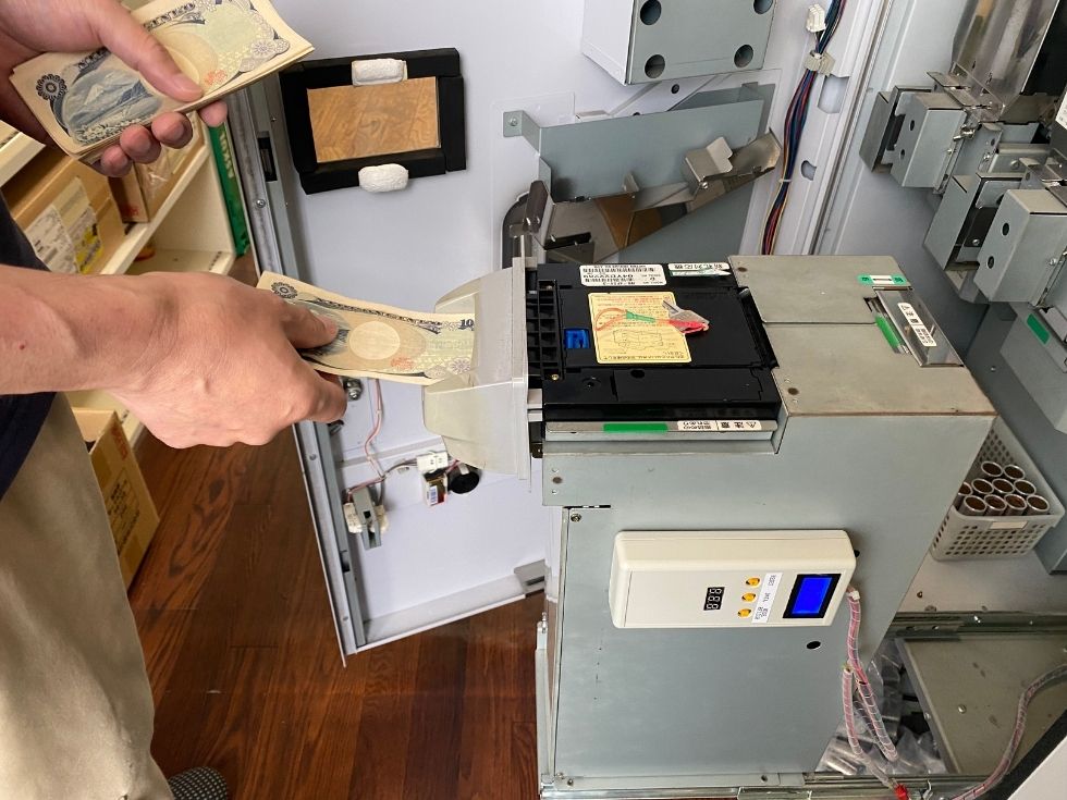 葛飾区の一二三交通自動車様でER-90M両替機を出張修理し、専用チェッカーで故障原因を確認している様子